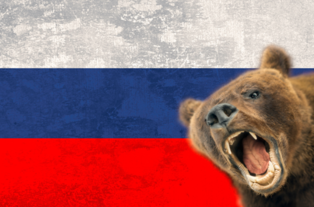 An image of a growling bear in front of the Russian flag.