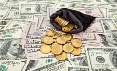 An image of a coins purse with gold coins on a layer of dollar bills, signaling increase gold purchases.