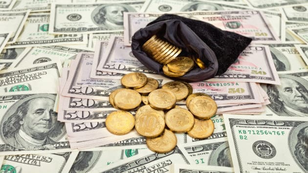 An image of a coins purse with gold coins on a layer of dollar bills, signaling increase gold purchases.
