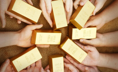 An image of hands grabbing gold bars to illustrate that gold is the second-most popular investment asset.